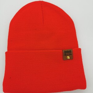 May include: A bright red beanie with a brown leather patch that says "Handmade with love by Fashion Finds".