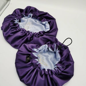 Puede incluir: Dos gorros para el cabello de satén morado con forro de satén azul claro. Los gorros tienen un cierre de cordón.