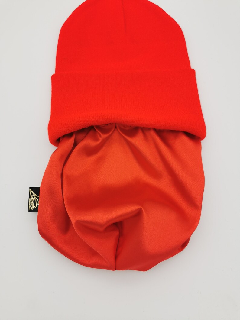 May include: A bright red beanie with a matching red satin lining. The beanie is folded down to show the lining.