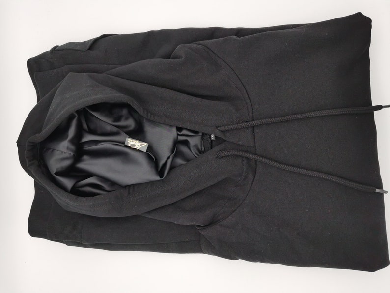May include: Black hooded sweatshirt with a satin lining. The hood is folded down and the drawstring is visible.