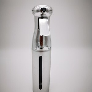 May include: A silver spray bottle with a clear window to see the liquid level. The bottle has a trigger sprayer and a cap.