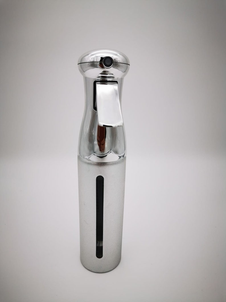 May include: A silver spray bottle with a clear window to see the liquid level. The bottle has a trigger sprayer and a cap.