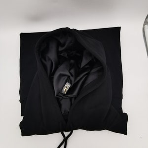 May include: Black hooded sweatshirt with a satin lining. The hood is folded down and the drawstring is visible.