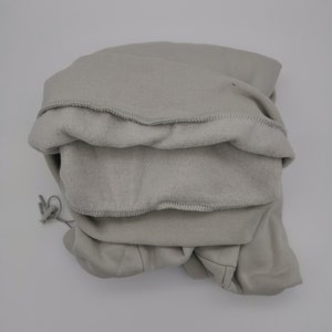 May include: A gray hooded sweatshirt folded neatly. The hood is turned inside out, revealing the soft fleece lining.