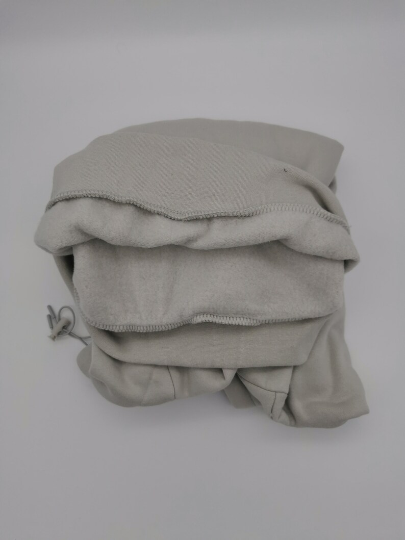 May include: A gray hooded sweatshirt folded neatly. The hood is turned inside out, revealing the soft fleece lining.