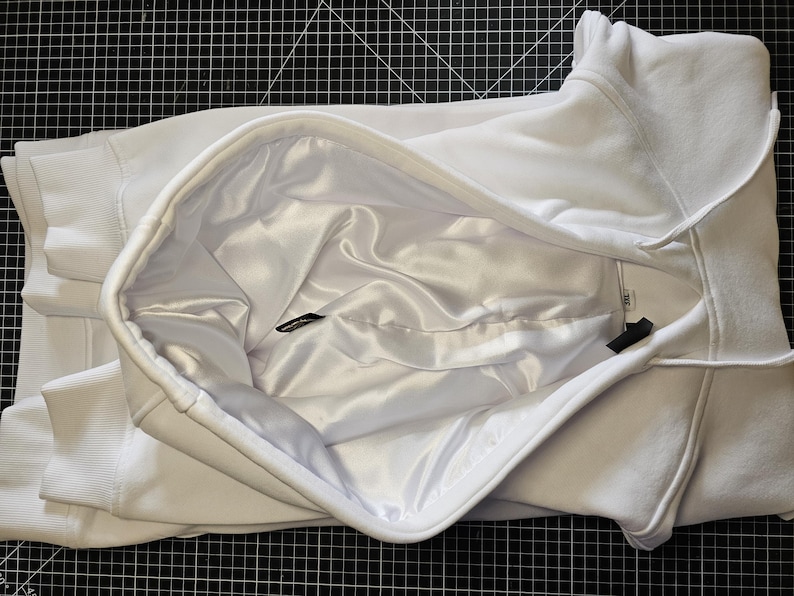 May include: White hooded sweatshirt with a satin lining. The hood is folded back to reveal the lining.