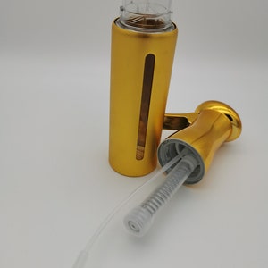 May include: Gold metal soap dispenser bottle with a clear plastic pump and a clear plastic tube. The bottle is separated from the pump and tube.