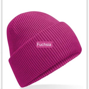 May include: A fuchsia colored knitted beanie hat. The hat is ribbed and has a fold-over brim.