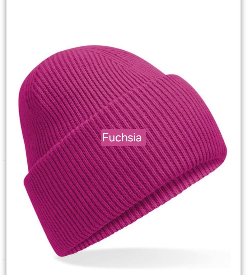 May include: A fuchsia colored knitted beanie hat. The hat is ribbed and has a fold-over brim.