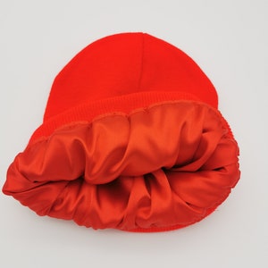May include: A bright red beanie with a satin lining. The beanie is turned inside out to show the lining.