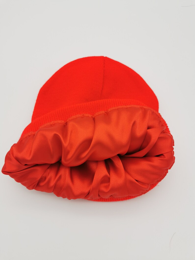 May include: A bright red beanie with a satin lining. The beanie is turned inside out to show the lining.