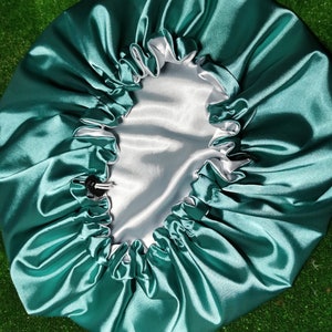 Pu&ograve; includere: Un cappuccio in raso verde acqua con fodera in raso bianco. Il cappuccio ha un elastico per una vestibilit&agrave; sicura e una chiusura con coulisse. Il tessuto lucido riflette la luce.