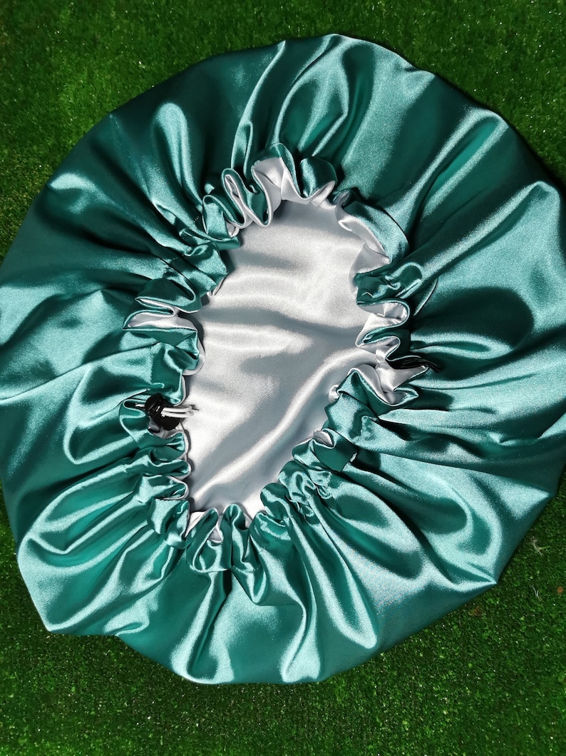 Pu&ograve; includere: Un cappuccio in raso verde acqua con fodera in raso bianco. Il cappuccio ha un elastico per una vestibilit&agrave; sicura e una chiusura con coulisse. Il tessuto lucido riflette la luce.