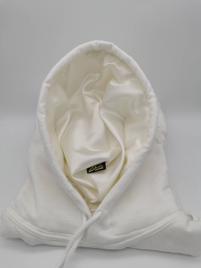 May include: White hooded sweatshirt with a white satin lining and a small black label with gold lettering that says "Signature Brand" inside the hood.