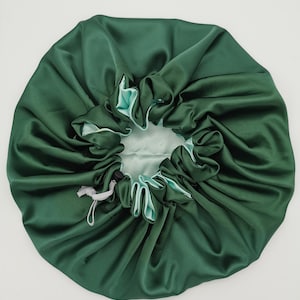 Pode incluir: Um gorro de dormir de cetim verde com forro verde claro e fecho de cordão.