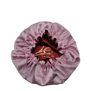 May include: Pink satin bonnet with a burgundy lining and gold lettering that reads "AS Bonne"