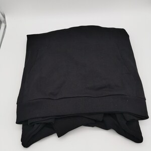 May include: A black hooded sweatshirt folded on a white surface.
