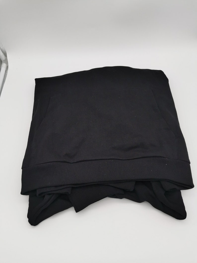 May include: A black hooded sweatshirt folded on a white surface.