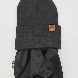 May include: A black beanie with a brown leather patch that says "Handmade with love for the fearless soul". The beanie has a matching black neck gaiter.