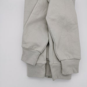 May include: A folded gray sweatshirt with long sleeves and a ribbed cuff.