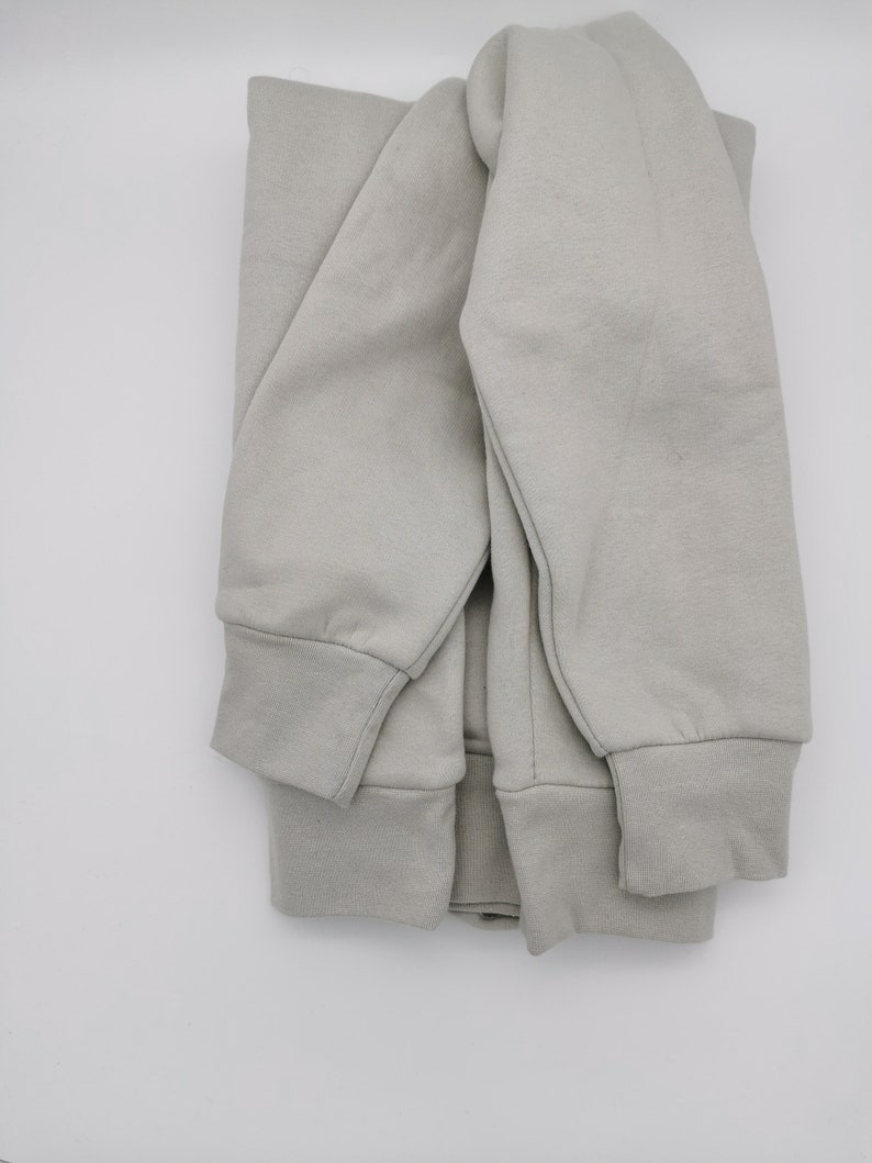 May include: A folded gray sweatshirt with long sleeves and a ribbed cuff.