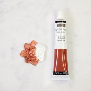 May include: A tube of copper wax for decorating and finishing projects. The tube is labeled "Decor Wax, Cire Cera, Corona Copper, CUE Corona, Corona de Cobre" and is 1.69 fluid ounces (50 ml).