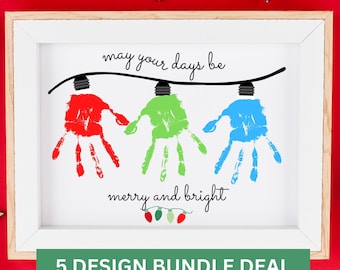 May include: A framed print featuring three handprints in red, green, and blue, hanging from a black string of lights. The text reads "may your days be merry and bright" with a small graphic of three colored light bulbs at the bottom of the print.