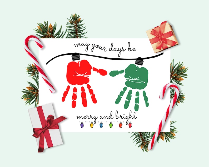 May include: A white rectangular holiday card featuring a red handprint and a green handprint hanging from a black string of lights. The text reads "may your days be" above the prints and "merry and bright" below, with small colorful light bulbs.