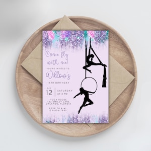 May include: A lilac invitation with the text "Come fly with me!" and details for a 14th birthday party. Silhouettes of aerial performers are featured. The invitation is on a wooden tray with a brown envelope.