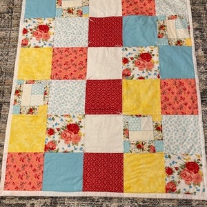 May include: A patchwork quilt with a variety of floral patterns in shades of red, pink, yellow, blue, and white. The quilt is made up of 16 squares, each with a different pattern.