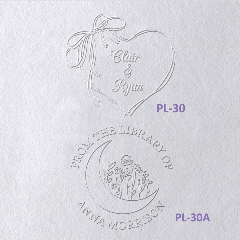 May include: Two embossed designs on white paper. The top design features a heart formed by a ribbon with the text Clair & Ryan and the code PL-30. The bottom design is a circular stamp with a crescent moon, flowers, and the text FROM THE LIBRARY OF ANNA MORRISON PL-30A.