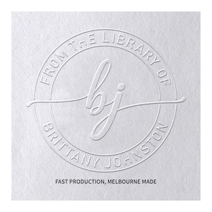 May include: A white circular embossed stamp design on textured paper featuring the text FROM THE LIBRARY OF BRITTANY JOHNSTON surrounding the cursive initials bj in the centre. The text FAST PRODUCTION, MELBOURNE MADE appears below.