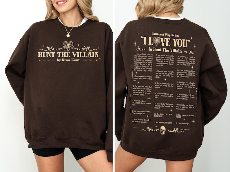 May include: A brown sweatshirt with the text "HUNT THE VILLAIN" and "by Rina Kent" in a gold font on the front. The back of the sweatshirt has the text "Different Way To Say 'I LOVE YOU' In Hunt The Villain".