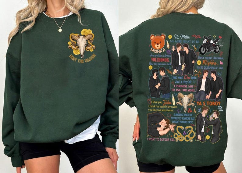 May include: Dark green sweatshirt with a white crew neck. The front features a skull with horns and the text "HUNT THE VILLAIN". The back has illustrations and text including "Mishka", "I love you Julian", and "YA S TOBOY".
