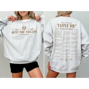 May include: Light gray sweatshirt with the text "HUNT THE VILLAIN" and "by Rina Kent" in brown. The back of the sweatshirt has the text "Different Way To Say 'I LOVE YOU' In Hunt The Villain" in brown.