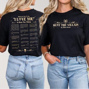 May include: Black t-shirt with gold text that reads "HUNT THE VILLAIN by Rina Kent" on the front. The back of the shirt has a list of phrases under the title "Different Way To Say 'I LOVE YOU' In Hunt The Villain".