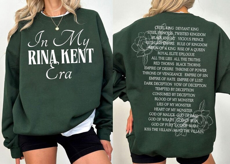 May include: Dark green sweatshirt with the text "In My Rina Kent Era" in white script on the front. The back features a list of phrases and a floral design in white. A casual, comfortable style.