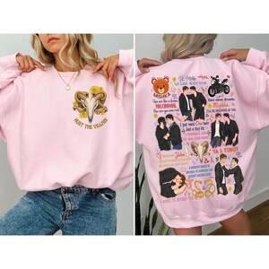 May include: Pink sweatshirt with a graphic on the front featuring a skull with horns and the text "HUNT THE VILLAIN". The back of the sweatshirt has multiple illustrations and text, including the words "Mishka" and "Volchonok".