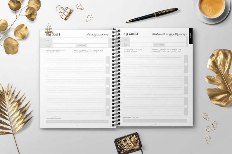 May include: A white planner with a black spiral binding. The planner has two pages open, each with the title "Big Goal" and space for writing down goals, milestones, and action plans. The text "Dream big, work hard" is written on the left page and "Think positive, enjoy the journey" is written on the right page.