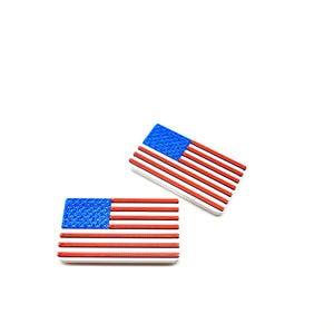 May include: Two rectangular American flag-themed decorative items. Each features a blue field with white stars and red and white stripes. The items are set against a white background.