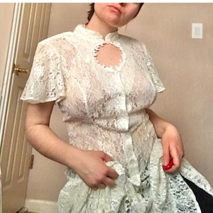 May include: A white lace dress with a round neckline and a button-up front. The dress has short sleeves and a flowing skirt.