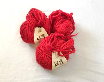May include: Three balls of red yarn with the label "Love Wool 100% Natural" on two of the balls.