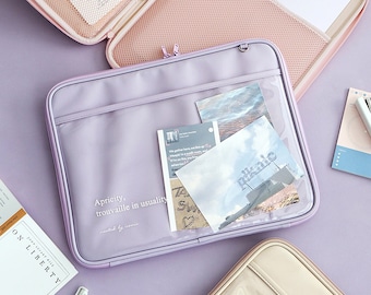 May include: A lavender laptop sleeve with a clear plastic pocket on the front. The pocket contains photos and a note that says "picnic". The sleeve has the text "Apricity, trouvaille in usuality" printed on the front.