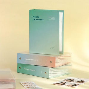 Op de afbeelding: Drie fotoalbums met een verloopontwerp in tinten groen en roze. De albums zijn gelabeld "Pieces of Moment" en zijn op elkaar gestapeld. Het bovenste album is een zakalbum met 10x15 cm fotozakjes.