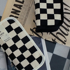 May include: Two black and white checkered pencil cases with a white border. The pencil cases have the text "Keep your ordinary - write, study, with style" on the front.