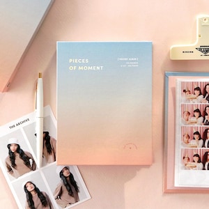 Op de afbeelding: Een blauw en roze ombre fotoalbum met de tekst "Pieces of Moment" en "Pocket Album" op de voorkant. Het album heeft 100 zakjes voor 10x15 cm foto's.