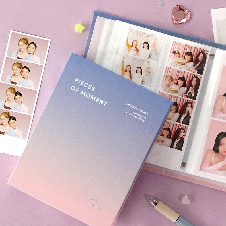 Op de afbeelding: Een roze en blauwe fotoalbum met de tekst "Pieces of Moment" op de omslag. Het album heeft 120 vakjes voor 4-delige fotoprints. Het album is open om een pagina met fotoprints te laten zien.