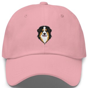May include: A pink baseball cap with an embroidered image of a Bernese Mountain Dog's head.
