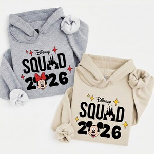 two Disney-themed hoodies, one gray and one beige, with the text "Disney SQUAD 2026" printed on them.