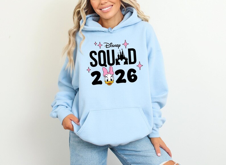 A woman wearing a light blue hoodie with a Disney-themed design and text.